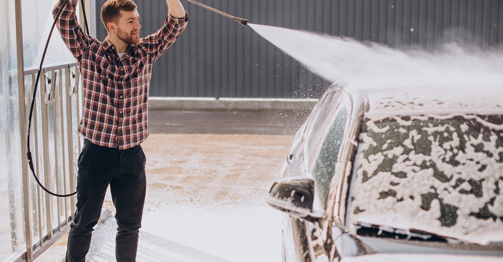 Young man washing his car at carwash